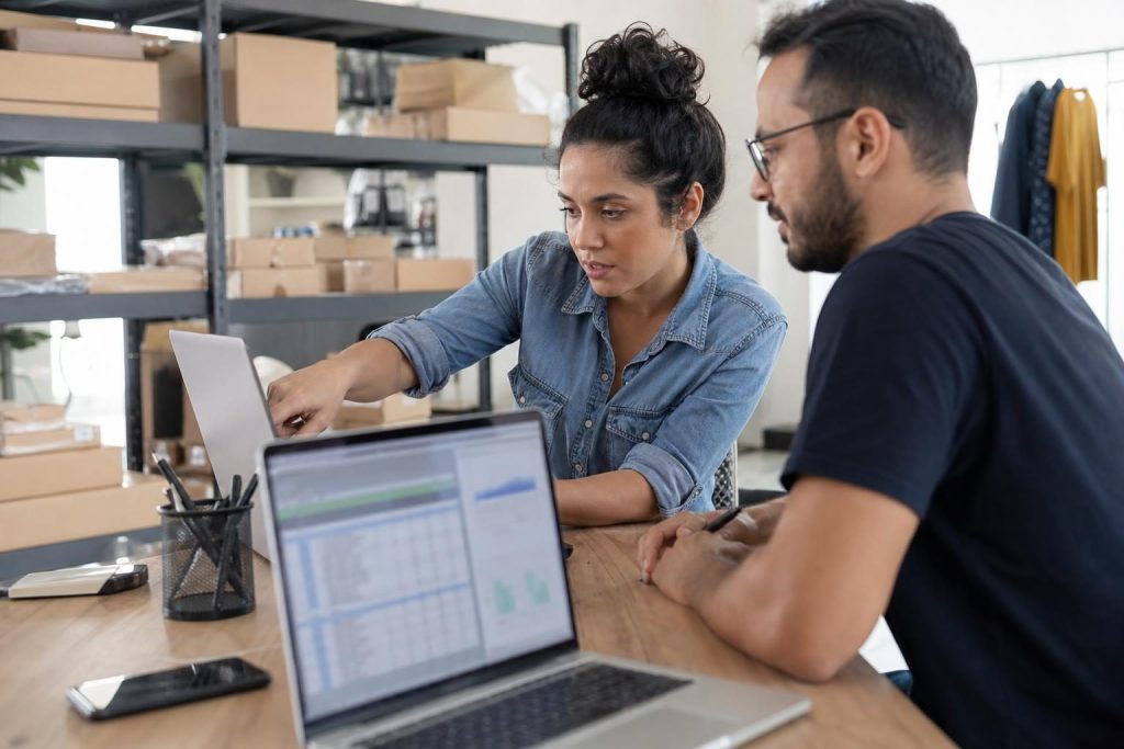 Equipe brasileira de e-commerce organizando fluxos de trabalho com IA em um escritório com produtos e pacotes