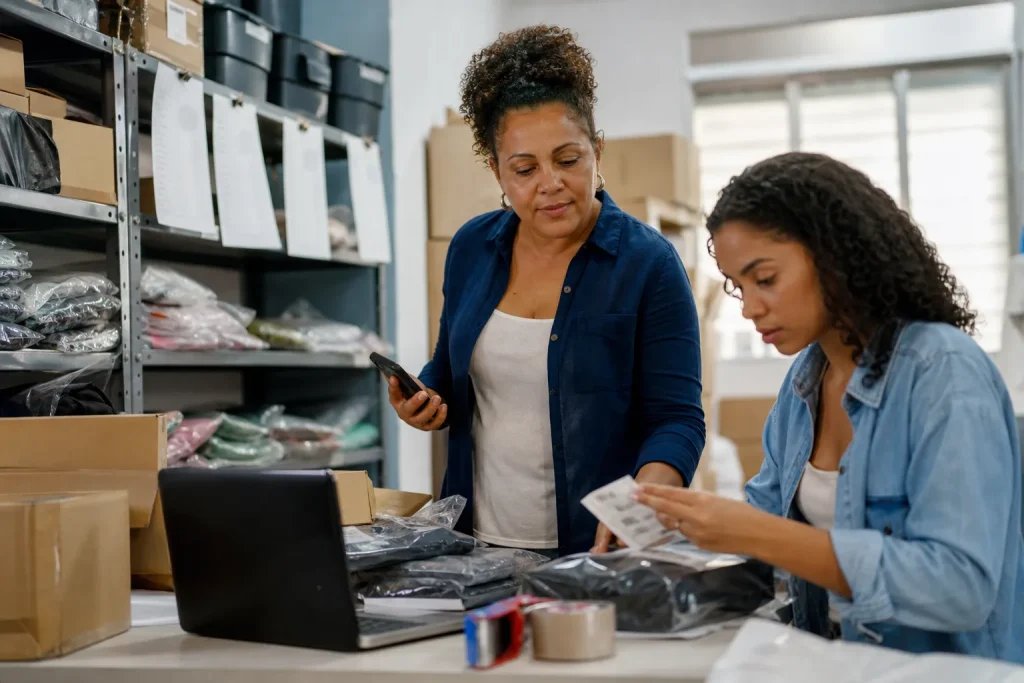 Equipe brasileira de e-commerce organizando estoque e pedidos para Black Friday com apoio de celular